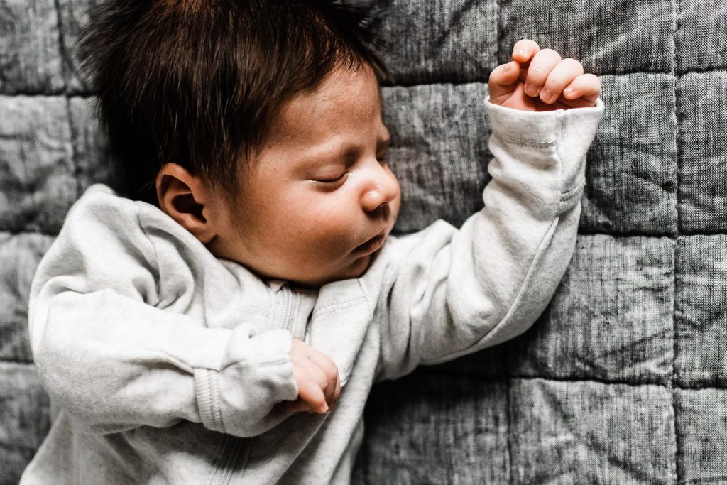 close up of newborn baby boy sleeping on a bed