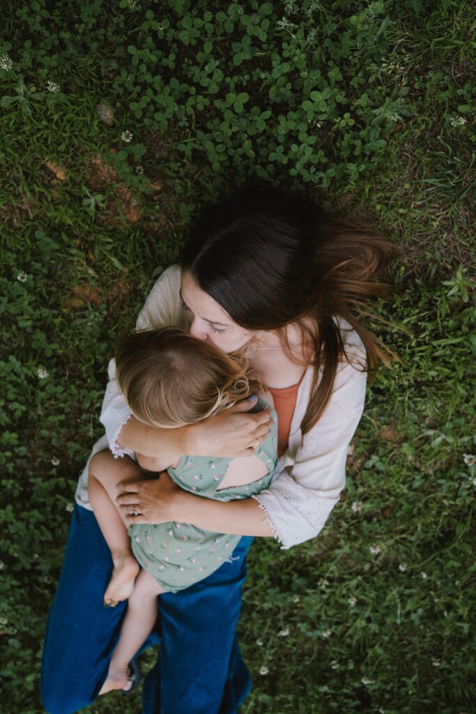 mother and daughter pose laying in the grass, lifestyle family photography