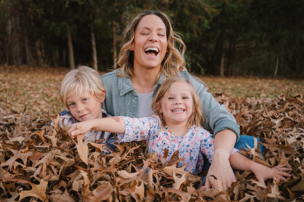 kids playing in the leaves with mom during fall family photos in Charlottesville