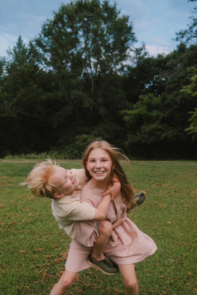 siblings playing in a field during family photos