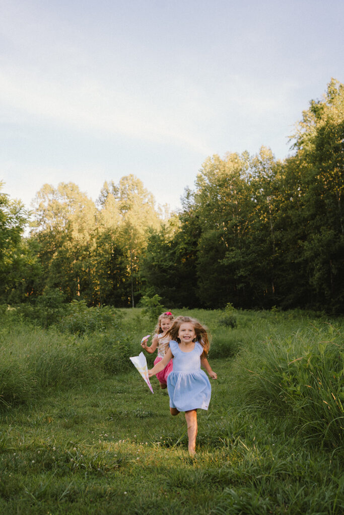 playful summer mini sessions in the with sisters running in a field