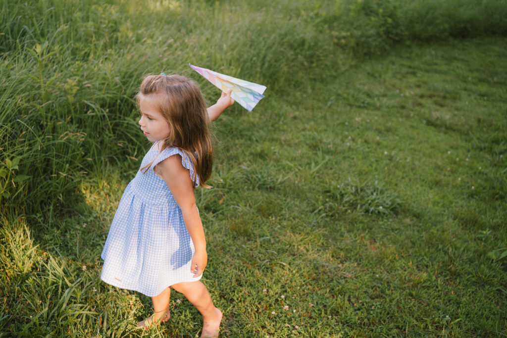 girl playing with paper airplane during summer mini sessions