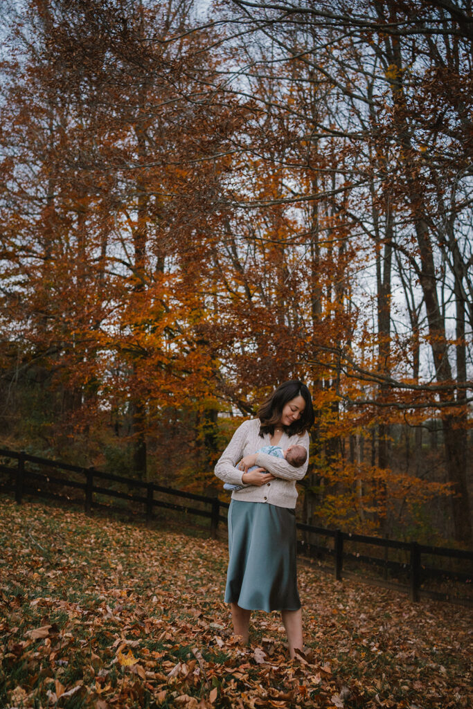 mother holding newborn baby outside in the fall